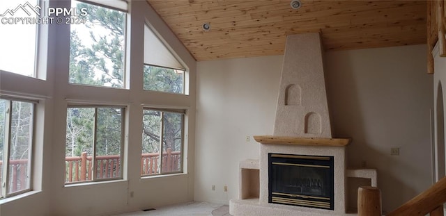 unfurnished living room with wooden ceiling, a large fireplace, carpet, and a healthy amount of sunlight