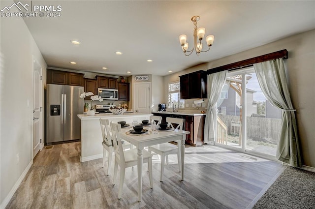 kitchen featuring light hardwood / wood-style floors, sink, appliances with stainless steel finishes, dark brown cabinets, and a kitchen island