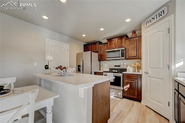 kitchen featuring stainless steel appliances, light hardwood / wood-style floors, a kitchen breakfast bar, and a center island