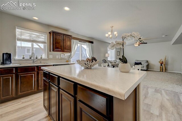 kitchen featuring a notable chandelier, sink, a kitchen island, light hardwood / wood-style flooring, and decorative light fixtures