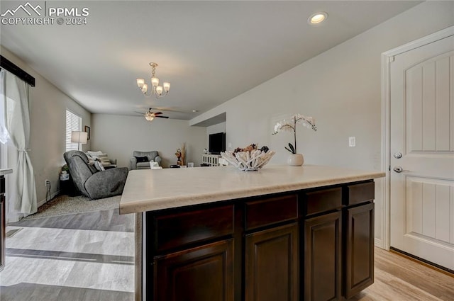 kitchen with light hardwood / wood-style floors, dark brown cabinets, a kitchen island, and ceiling fan with notable chandelier