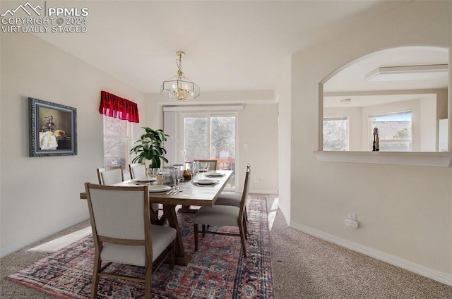 carpeted dining area with a wealth of natural light and a notable chandelier