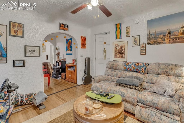 living room with hardwood / wood-style floors, ceiling fan, and a textured ceiling