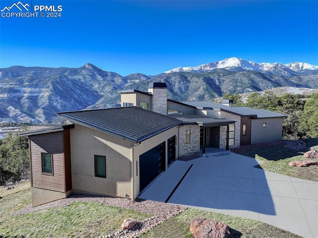 view of front of home with a standing seam roof, metal roof, concrete driveway, and a mountain view