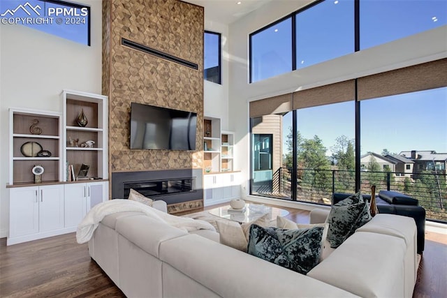 living area with a fireplace, a high ceiling, and wood finished floors