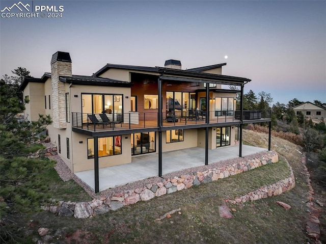 back of property with a chimney, a patio area, and stucco siding