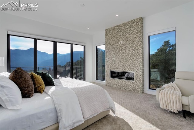 bedroom with a large fireplace, access to exterior, carpet, a mountain view, and recessed lighting