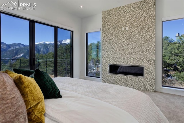 bedroom featuring carpet floors, recessed lighting, a mountain view, and a tile fireplace