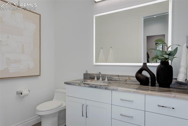 bathroom with toilet, baseboards, and vanity