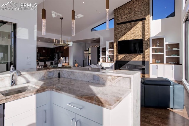 kitchen with open floor plan, wood finished floors, a sink, and light stone counters