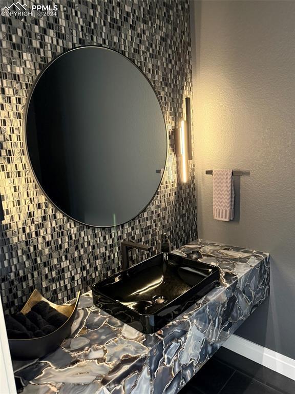 bathroom featuring baseboards, tasteful backsplash, a sink, and tile patterned floors