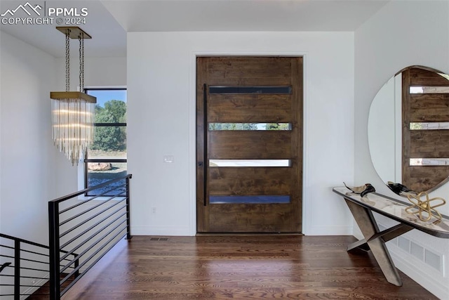 foyer entrance featuring a chandelier, wood finished floors, visible vents, and baseboards