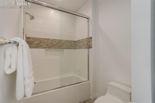 full bathroom featuring toilet and combined bath / shower with glass door