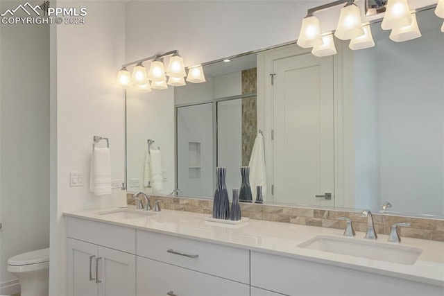 bathroom with double vanity, a sink, toilet, and a shower stall