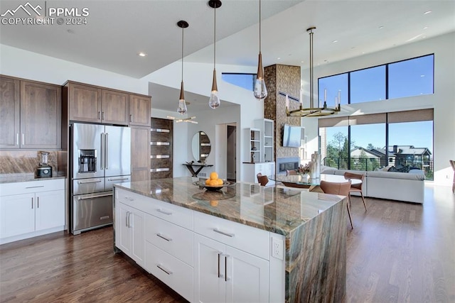 kitchen featuring a towering ceiling, dark stone counters, dark wood-type flooring, and high end fridge