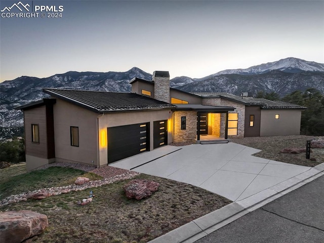 modern home featuring a garage, concrete driveway, metal roof, a standing seam roof, and a mountain view