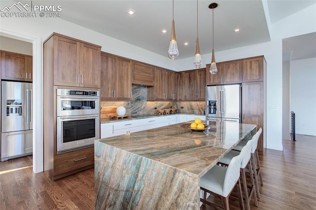 kitchen featuring stone counters, dark wood-style flooring, stainless steel appliances, decorative backsplash, and a kitchen island