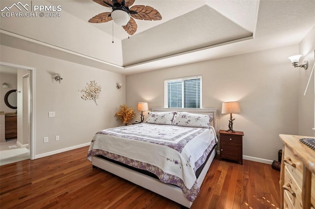 bedroom featuring ceiling fan, a textured ceiling, a raised ceiling, and dark hardwood / wood-style flooring