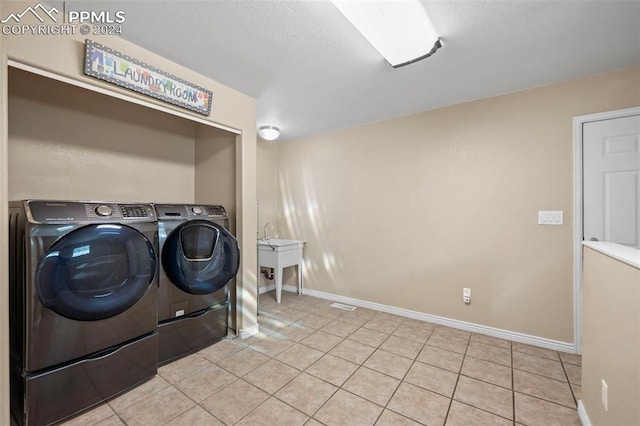 laundry room featuring sink, light tile patterned floors, and washer and clothes dryer