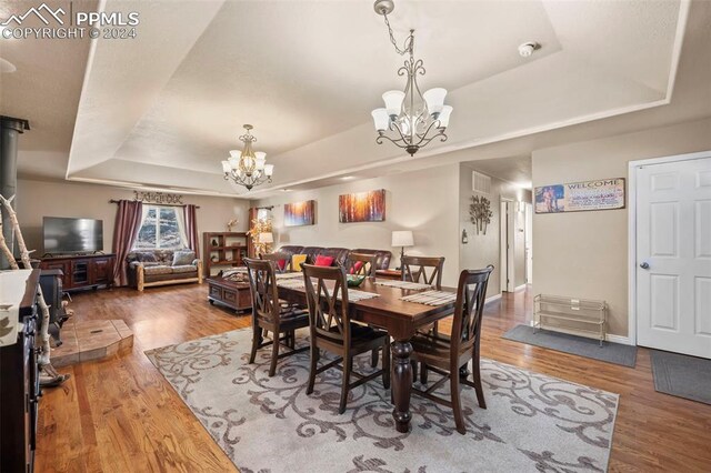 dining area featuring a chandelier, a tray ceiling, and hardwood / wood-style floors