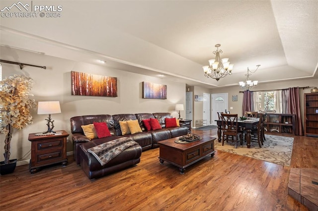 living room with hardwood / wood-style floors, a tray ceiling, and a notable chandelier