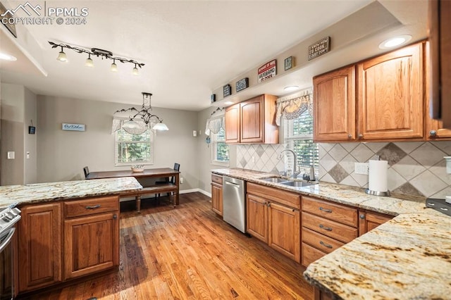 kitchen featuring light wood-type flooring, decorative light fixtures, decorative backsplash, sink, and stainless steel dishwasher