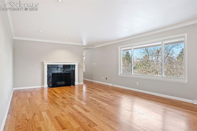 unfurnished living room featuring a fireplace, light hardwood / wood-style flooring, and crown molding