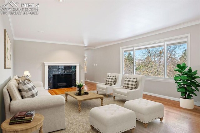 living room with ornamental molding, hardwood / wood-style flooring, and a high end fireplace