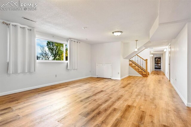 spare room with light wood-type flooring and a textured ceiling