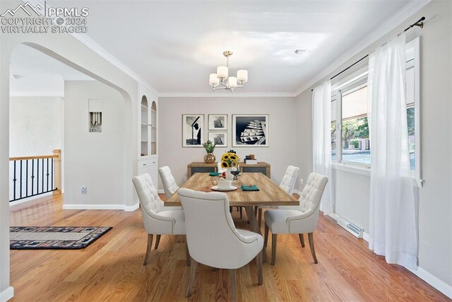 dining space featuring ornamental molding, light hardwood / wood-style floors, a chandelier, and built in shelves