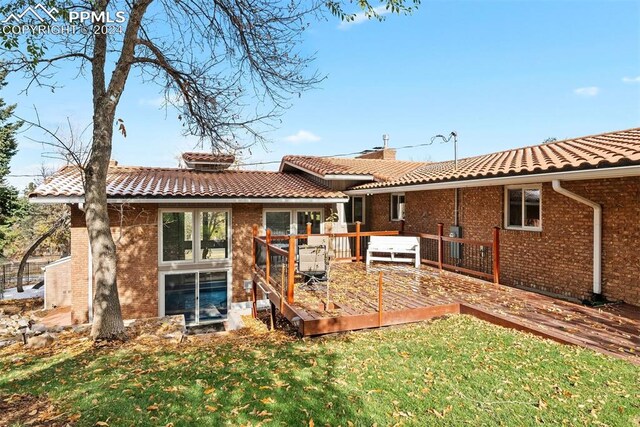 rear view of property featuring a deck and a lawn