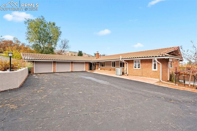 ranch-style home featuring central AC unit and a garage