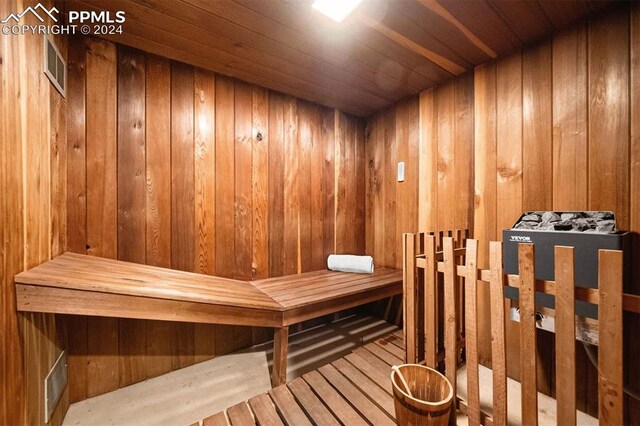 view of sauna featuring wooden walls, wood ceiling, and hardwood / wood-style flooring