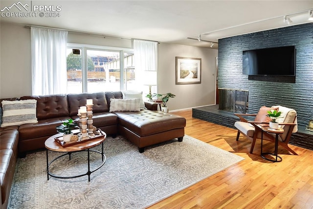 living room featuring a large fireplace, rail lighting, and wood-type flooring