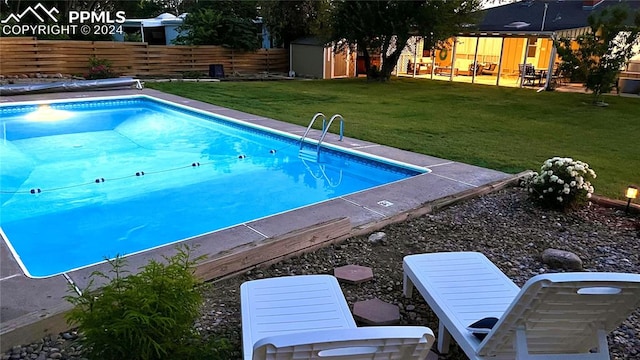 view of pool featuring a storage shed, a lawn, and a patio