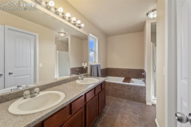 bathroom featuring vanity, a relaxing tiled tub, and tile patterned flooring