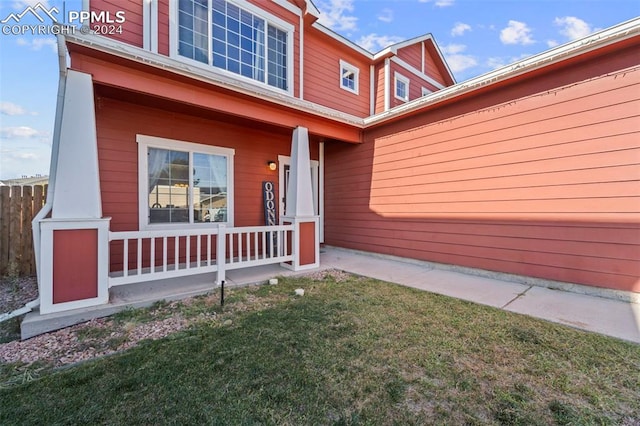 doorway to property with a porch and a yard