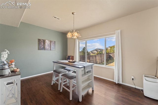 dining space with dark hardwood / wood-style floors and an inviting chandelier