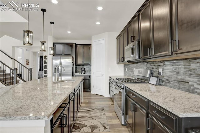 kitchen with stainless steel appliances, hardwood / wood-style flooring, an island with sink, and backsplash