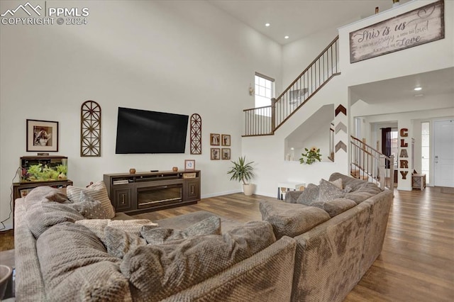 living room with a towering ceiling and wood-type flooring