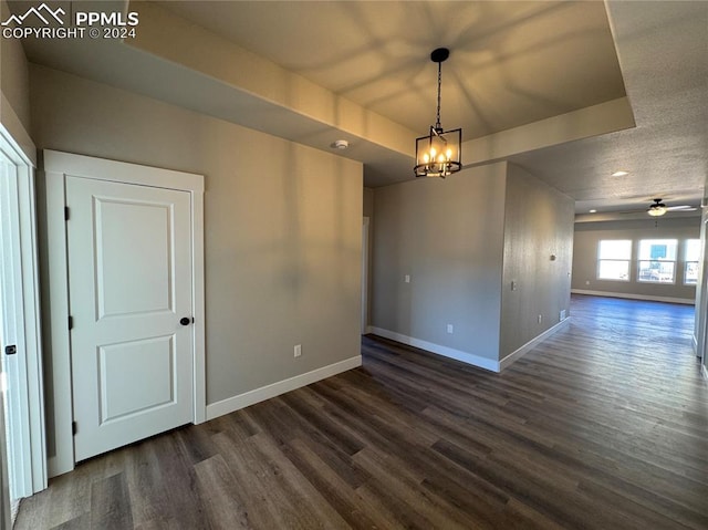 spare room featuring dark wood-type flooring and ceiling fan with notable chandelier