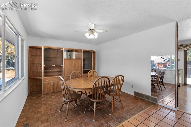 dining area with a textured ceiling, dark parquet floors, and ceiling fan