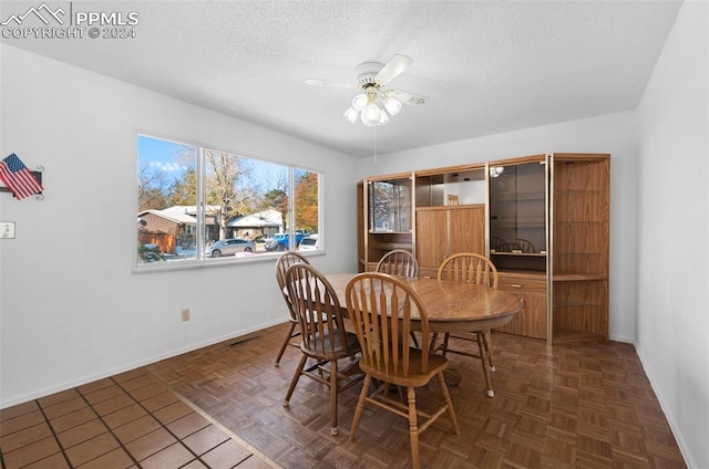 dining room featuring ceiling fan, dark parquet flooring, and a textured ceiling