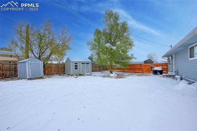 snowy yard with a storage shed