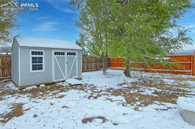 snowy yard featuring a storage shed