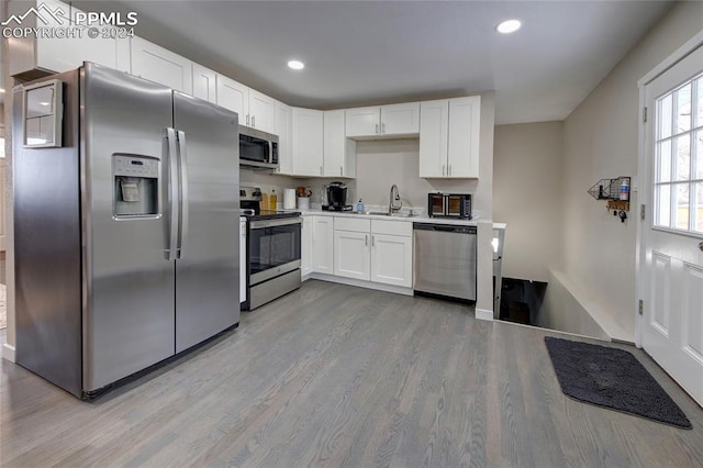 kitchen with light hardwood / wood-style flooring, white cabinetry, sink, and stainless steel appliances