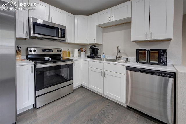 kitchen featuring stainless steel appliances, white cabinets, sink, and dark wood-type flooring