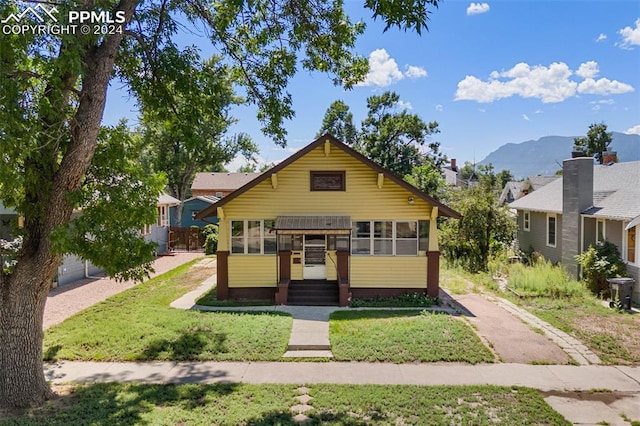 bungalow-style home featuring a mountain view and a front yard