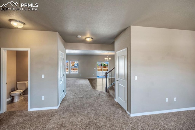 hallway with carpet, a textured ceiling, and a chandelier