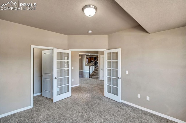 carpeted empty room featuring a textured ceiling and french doors